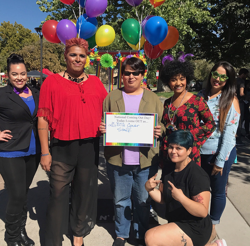 LGBTQRC Staff posing with a placard for National Coming Out Day